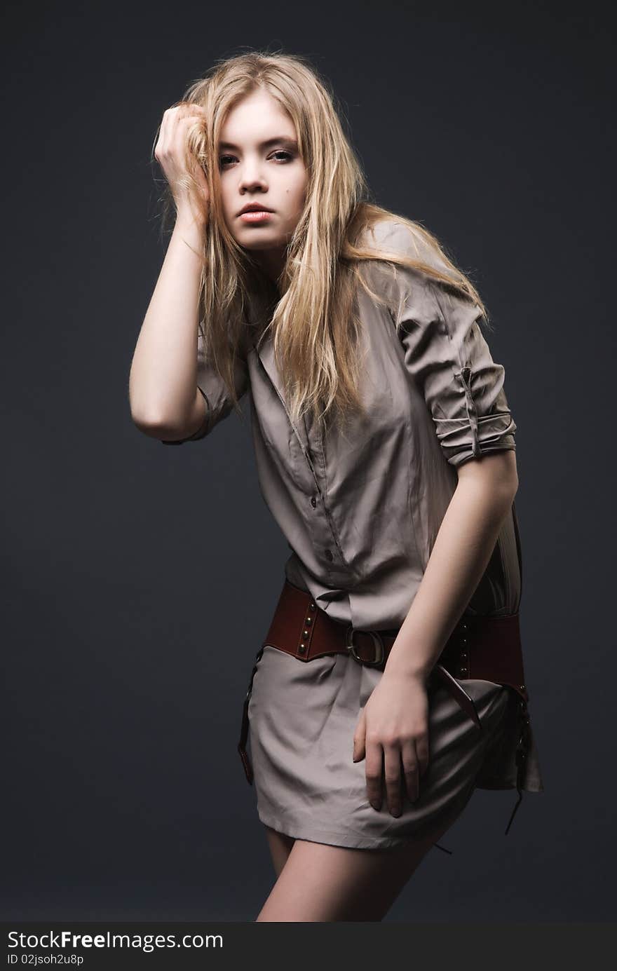 Fashion portrait of seductive blond girl with blowing hair on dark background