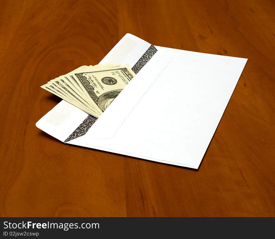 Dollar bills in a white envelope on the office desk. Dollar bills in a white envelope on the office desk.