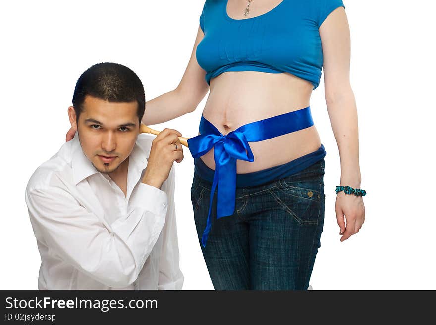 Pregnant girl with blue ribbon on her abdomen and her husband listening in their baby. Pregnant girl with blue ribbon on her abdomen and her husband listening in their baby.