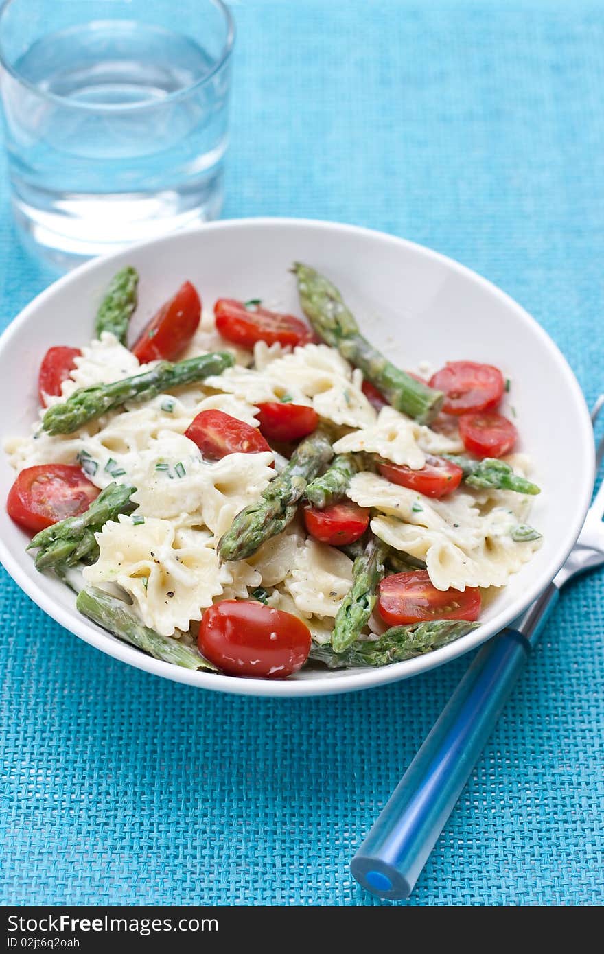 Dinner set with farfalle asparagus salad on a blue background. Dinner set with farfalle asparagus salad on a blue background