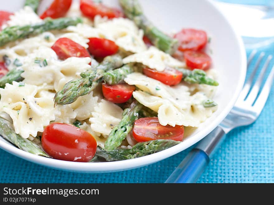 Dinner set with farfalle asparagus salad on a blue background. Dinner set with farfalle asparagus salad on a blue background