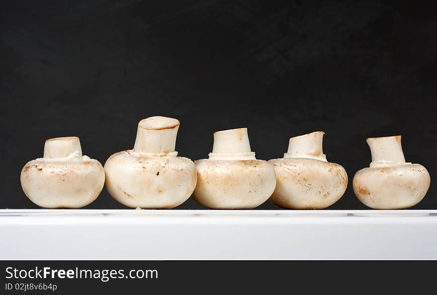 Fresh mushrooms on a white table against the wall