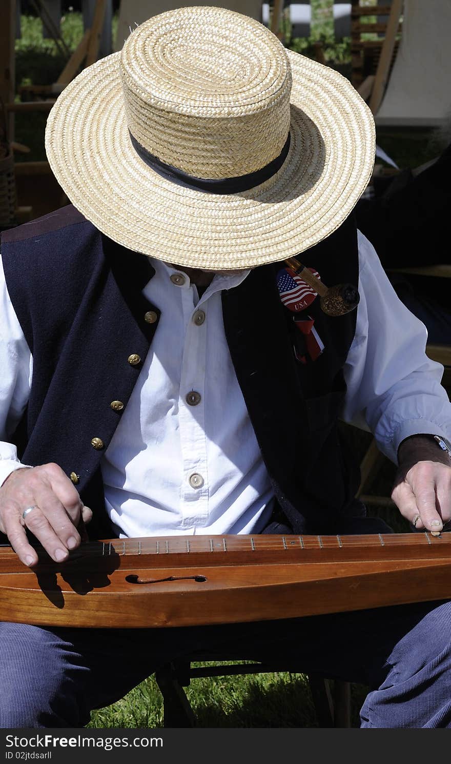 Man in a straw hat plays a dulcimer at a Civil War festival. Vertical shot. Man in a straw hat plays a dulcimer at a Civil War festival. Vertical shot