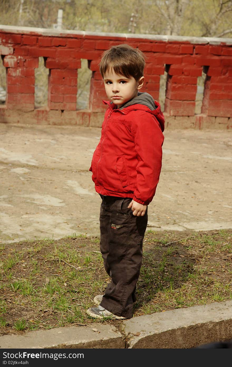 Beautiful little boy in red jacket with serious look, outdoor shot. Beautiful little boy in red jacket with serious look, outdoor shot