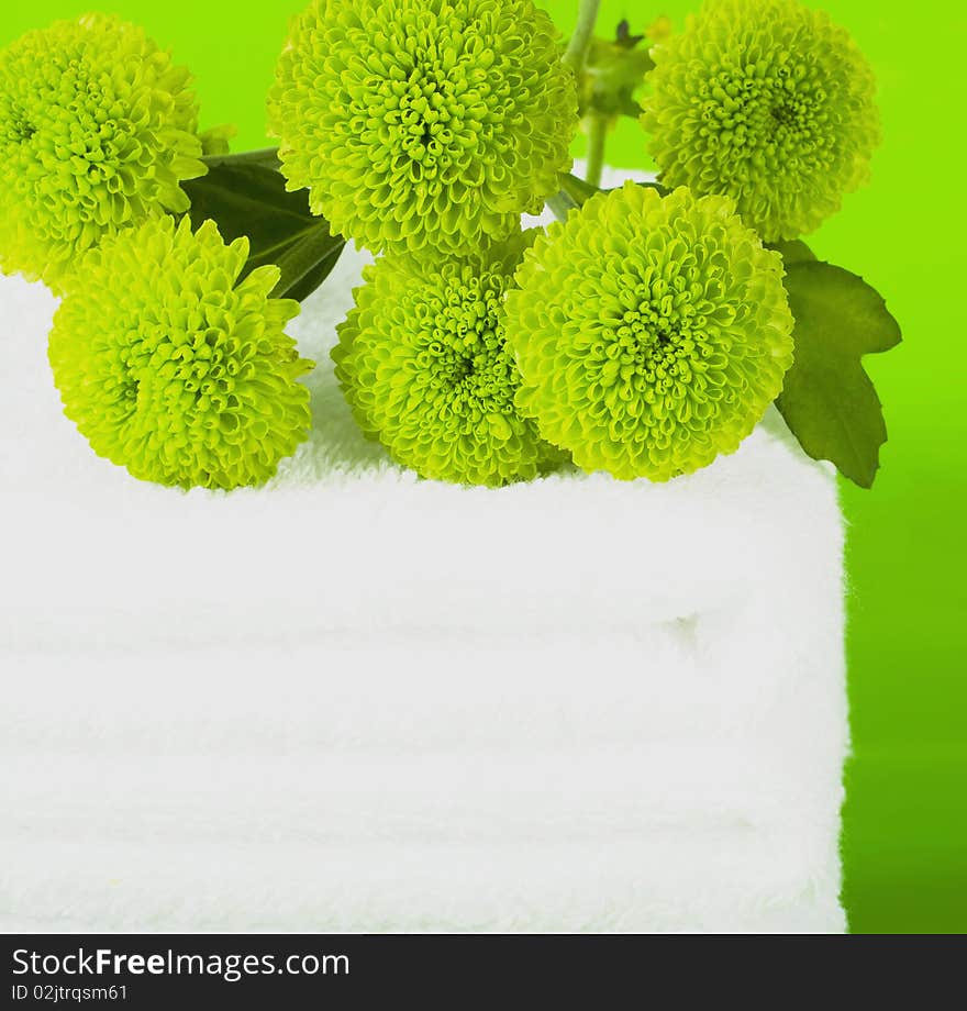 Pile white towels on green background and branch chrysanthemums