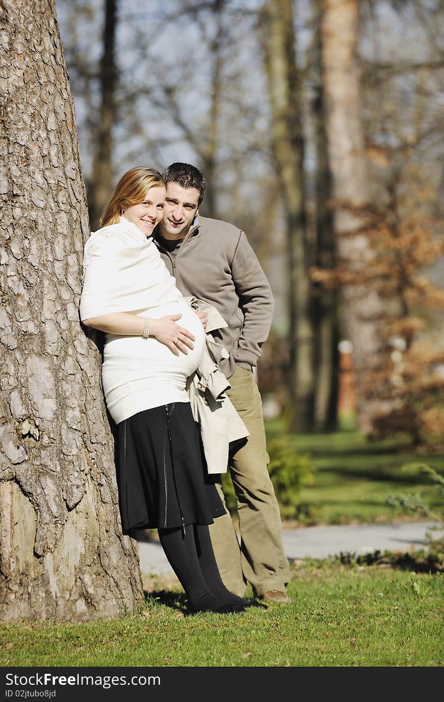 Happy young married family couple outdoor in nature have fun and waiting baby and representing young family growth and pregnancy concept. Happy young married family couple outdoor in nature have fun and waiting baby and representing young family growth and pregnancy concept