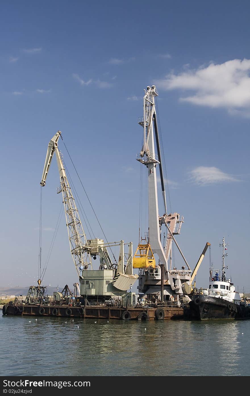 Two white cranes in a harbor on water's edge. Two white cranes in a harbor on water's edge