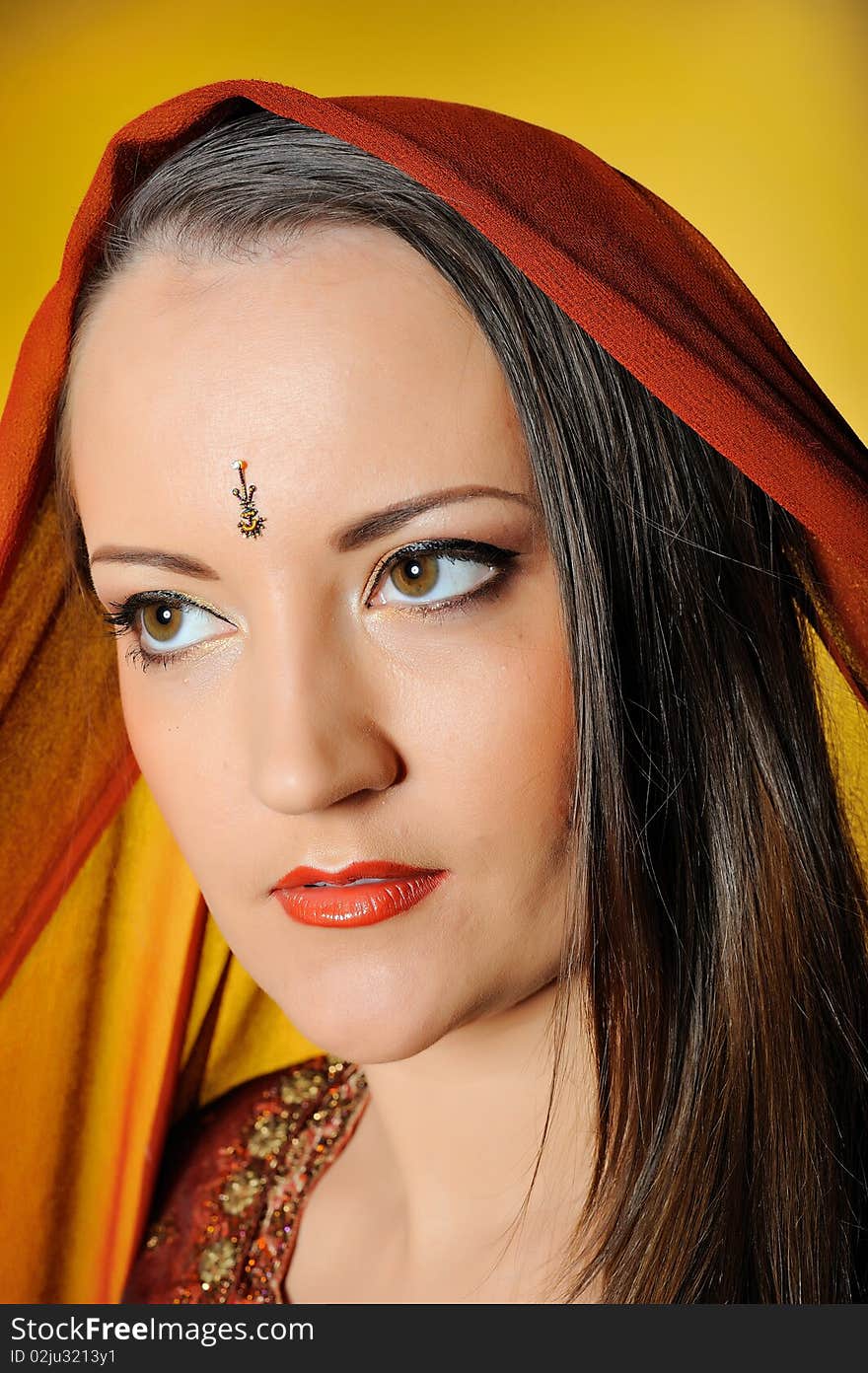 Young beautiful woman in indian traditional jewellary, bindi and sari dress. yellow background. Young beautiful woman in indian traditional jewellary, bindi and sari dress. yellow background