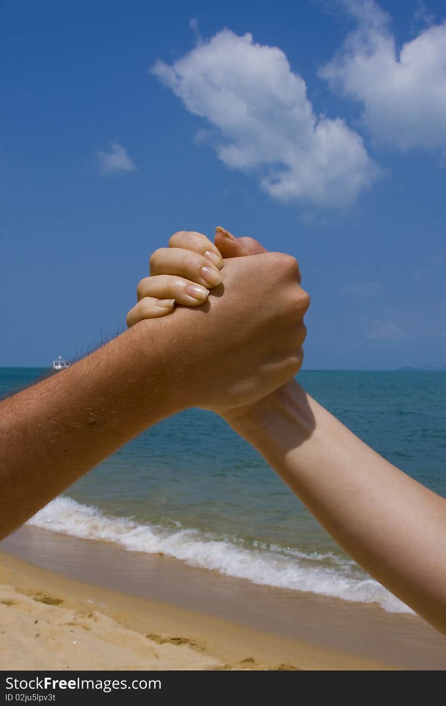 Couple hands in a sky and sea close-up