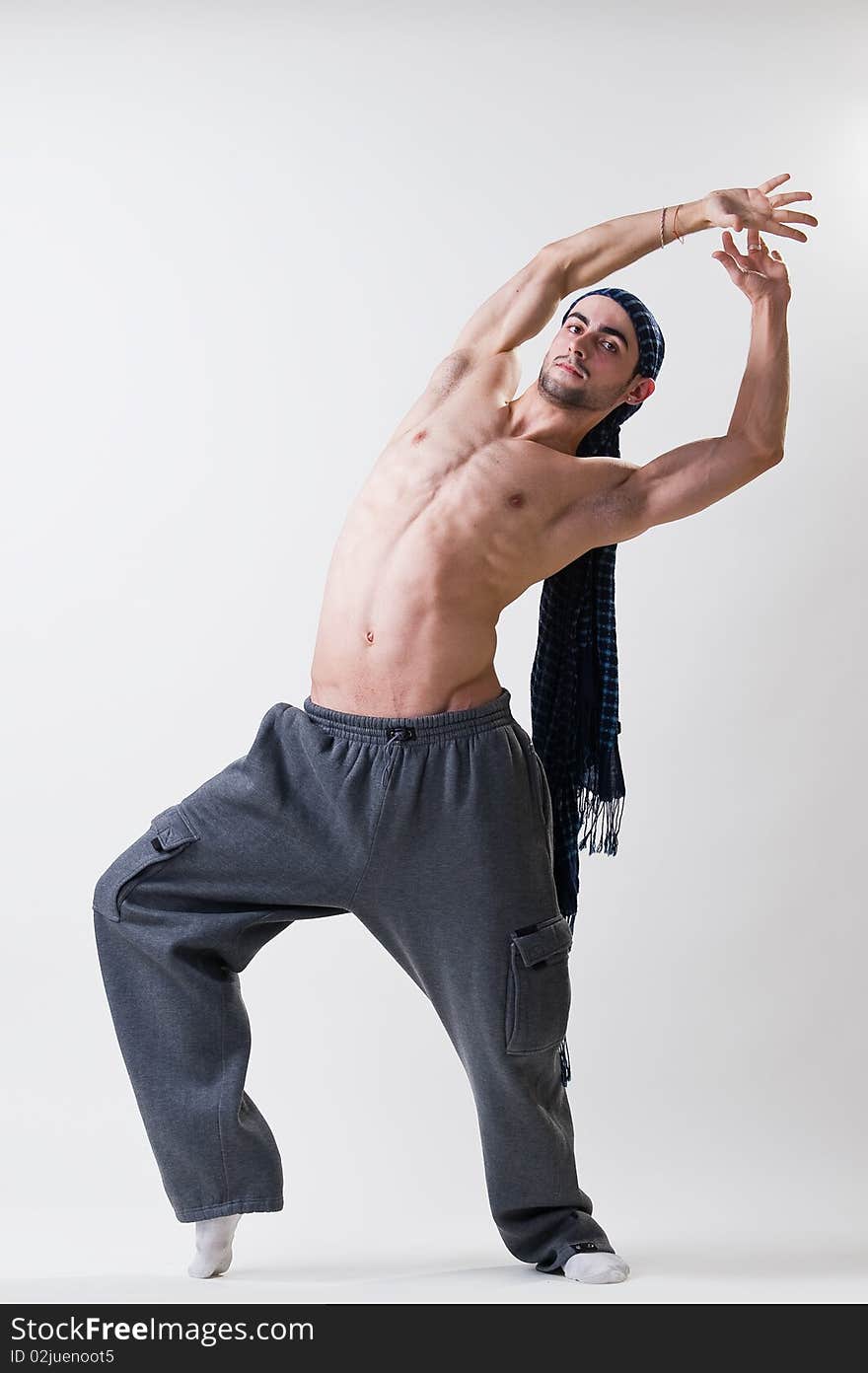 Handsome dancer exercising, studio shot over gray background