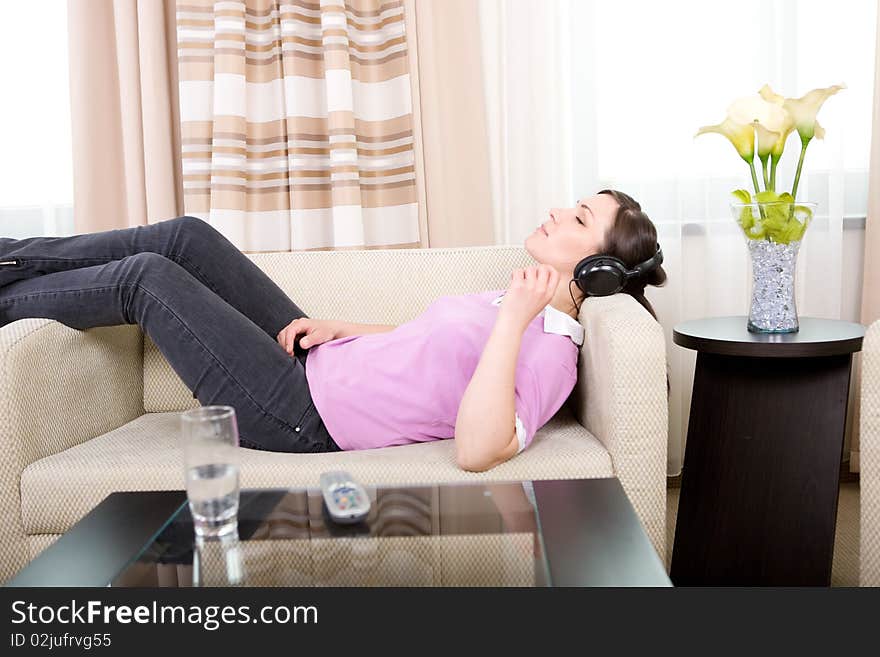 Young adult brunette woman with headphones on sofa. Young adult brunette woman with headphones on sofa