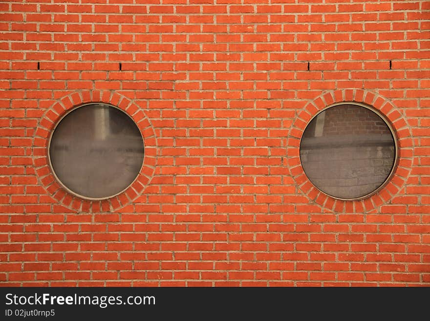 Closeup on round reflective openings in a red brick wall. Closeup on round reflective openings in a red brick wall