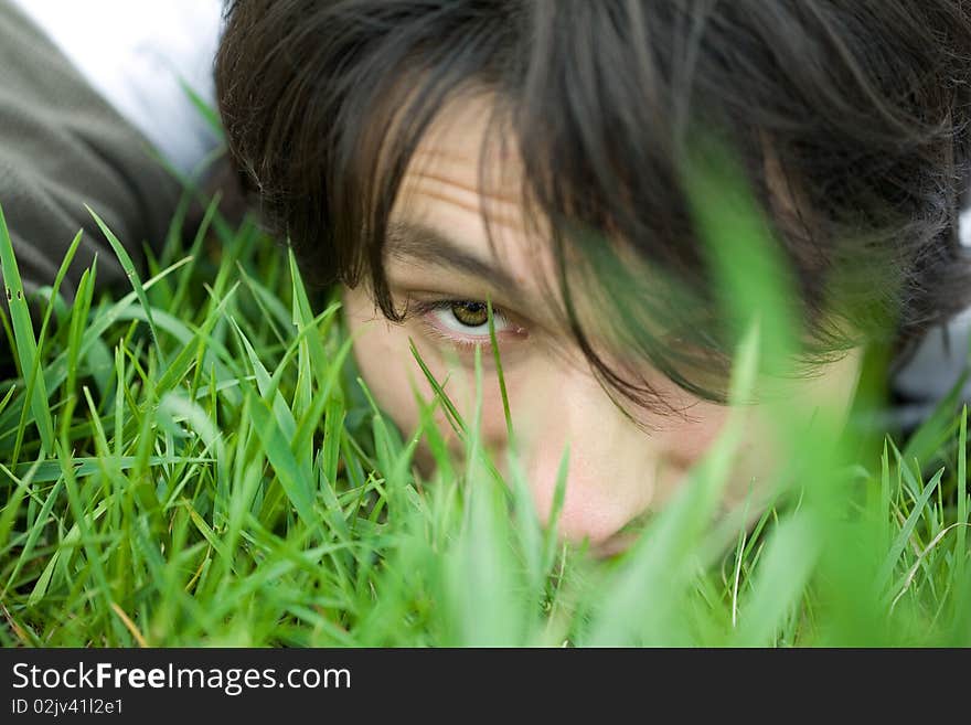 Face of a young man lying on the grass. Eye closeup. Face of a young man lying on the grass. Eye closeup