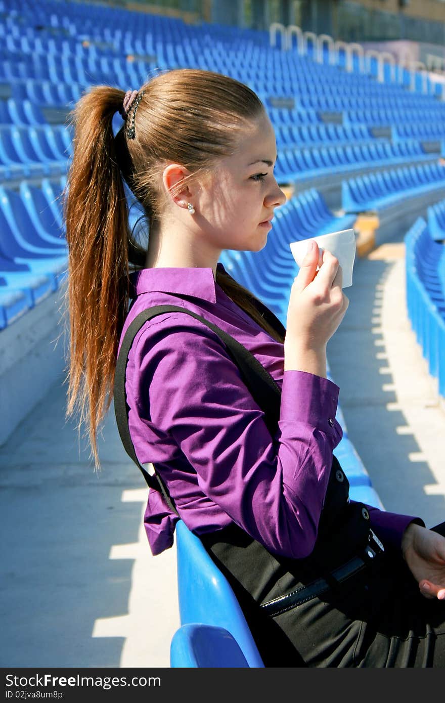 Young businesswoman drinking tea at the stadium