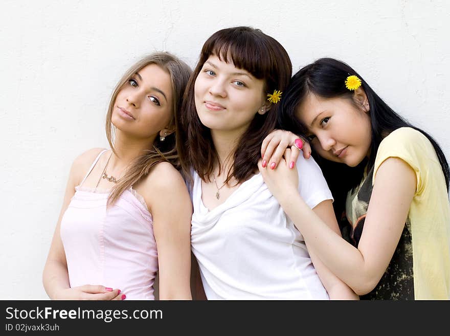 Three female friends standing in front of a white wall