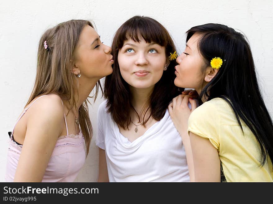 Three female friends standing in front of a white wall