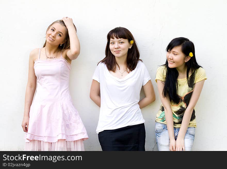 Three female friends standing in front of a white wall