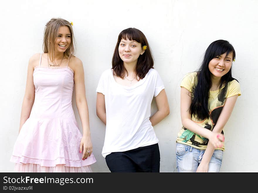 Three female friends standing in front of a white wall