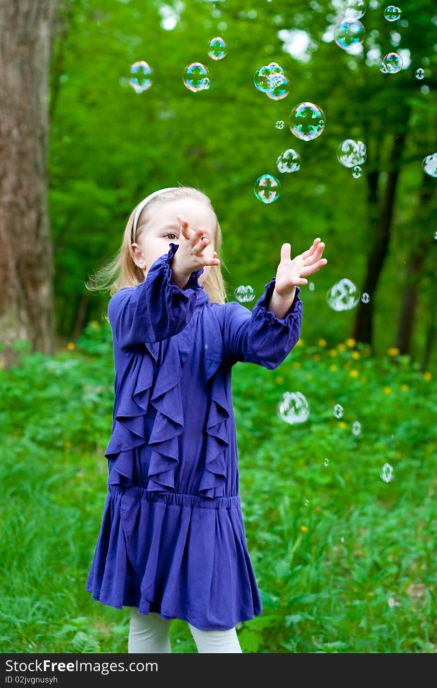 Little girl in park catching bubbles. Outdoor shot. Little girl in park catching bubbles. Outdoor shot