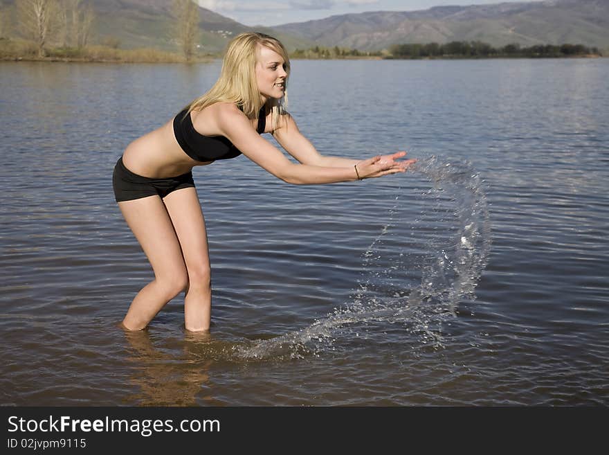 A woman playing in the water by splashing and throwing the water in the air. A woman playing in the water by splashing and throwing the water in the air.