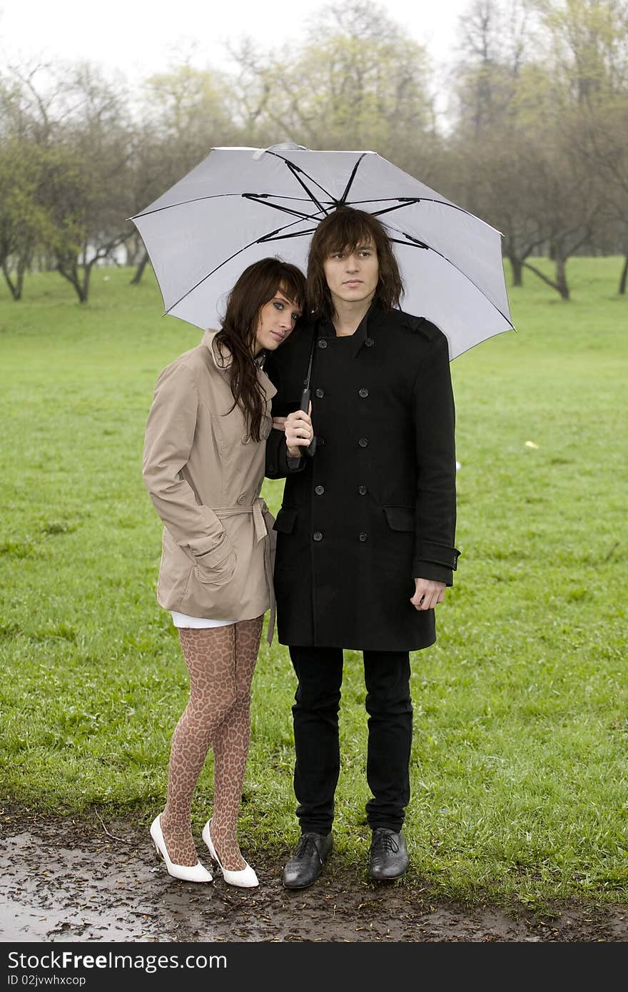 Young couple under umbrella in the park