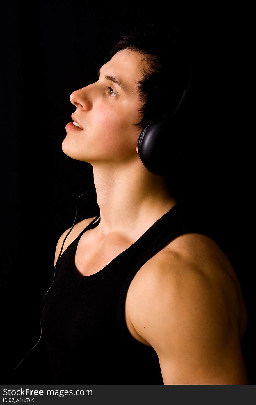 Young Man listening to music with headphones, on black background. Young Man listening to music with headphones, on black background