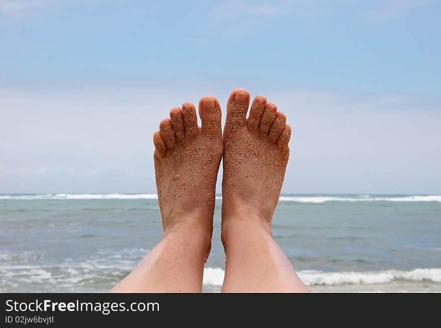 Sandy bare feet against Hawaii island ocean