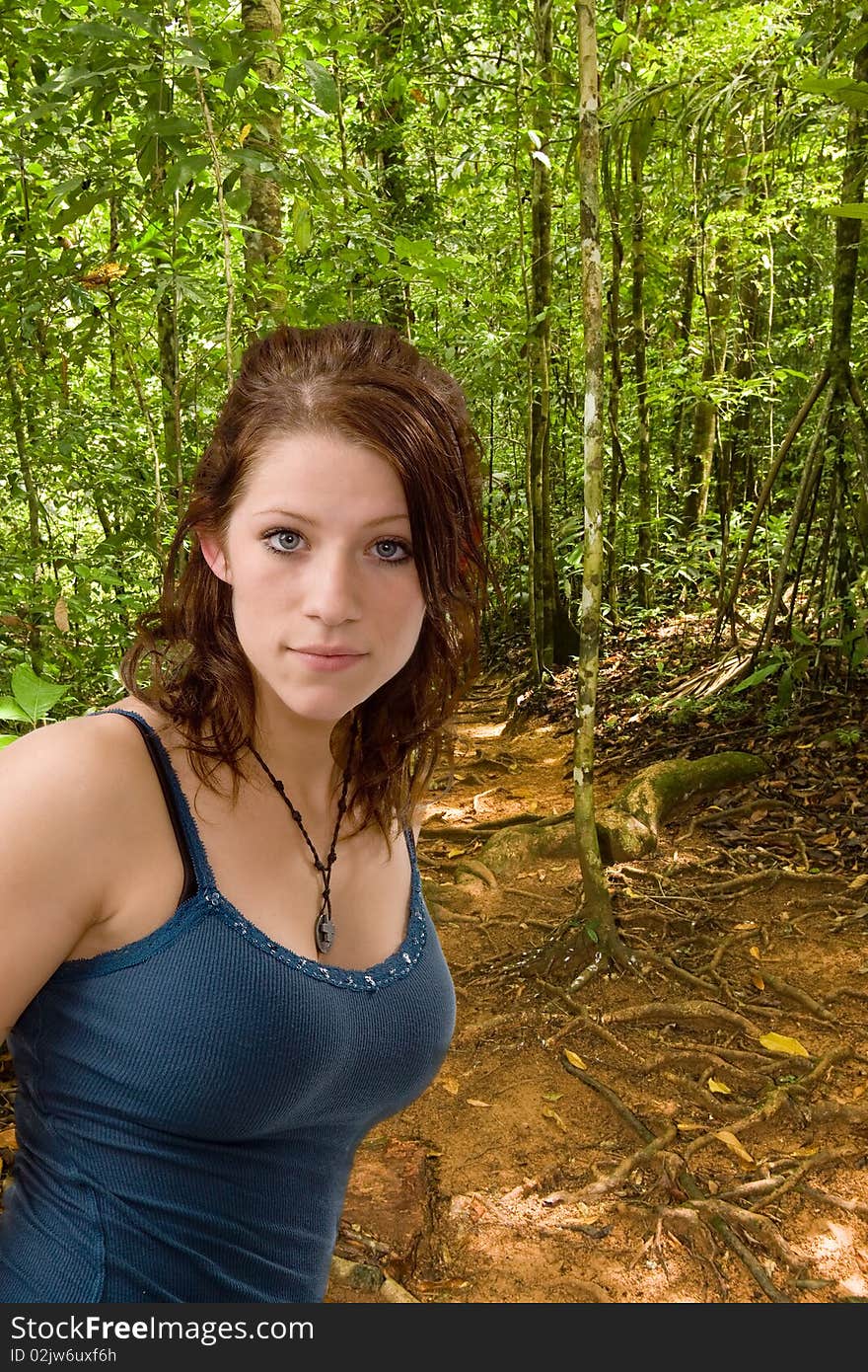 Pretty young woman in blue hiking along a forest trail. Pretty young woman in blue hiking along a forest trail.