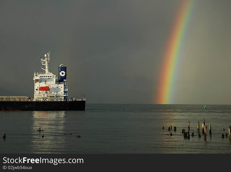 Rainbow and stern of a cargo ship