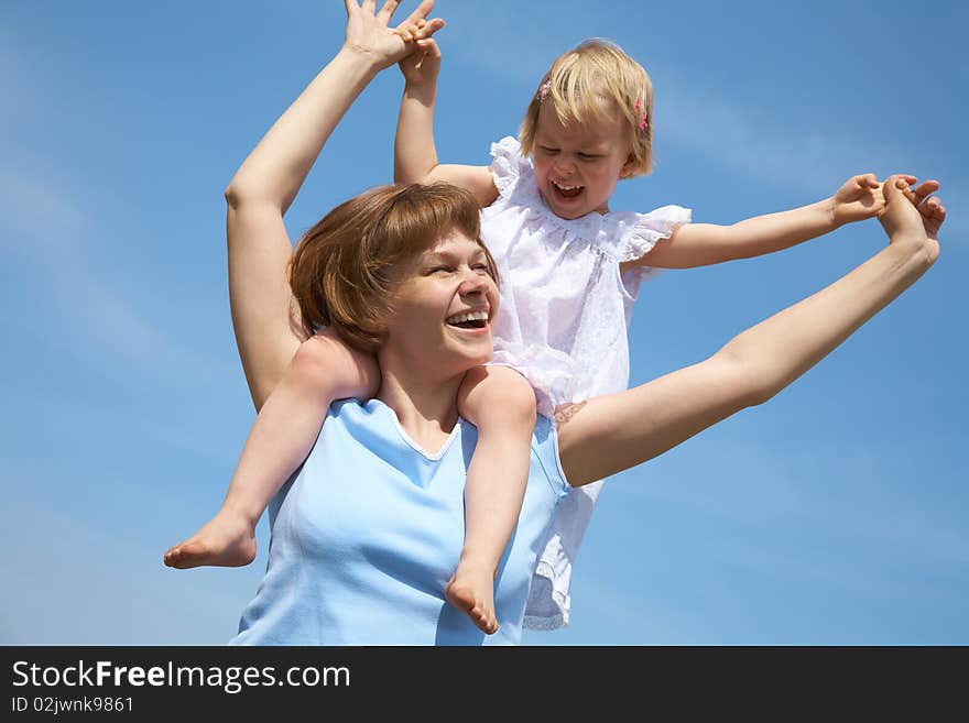 Happy mother has a good summer time with her little daughter background on the blue sky. Happy mother has a good summer time with her little daughter background on the blue sky