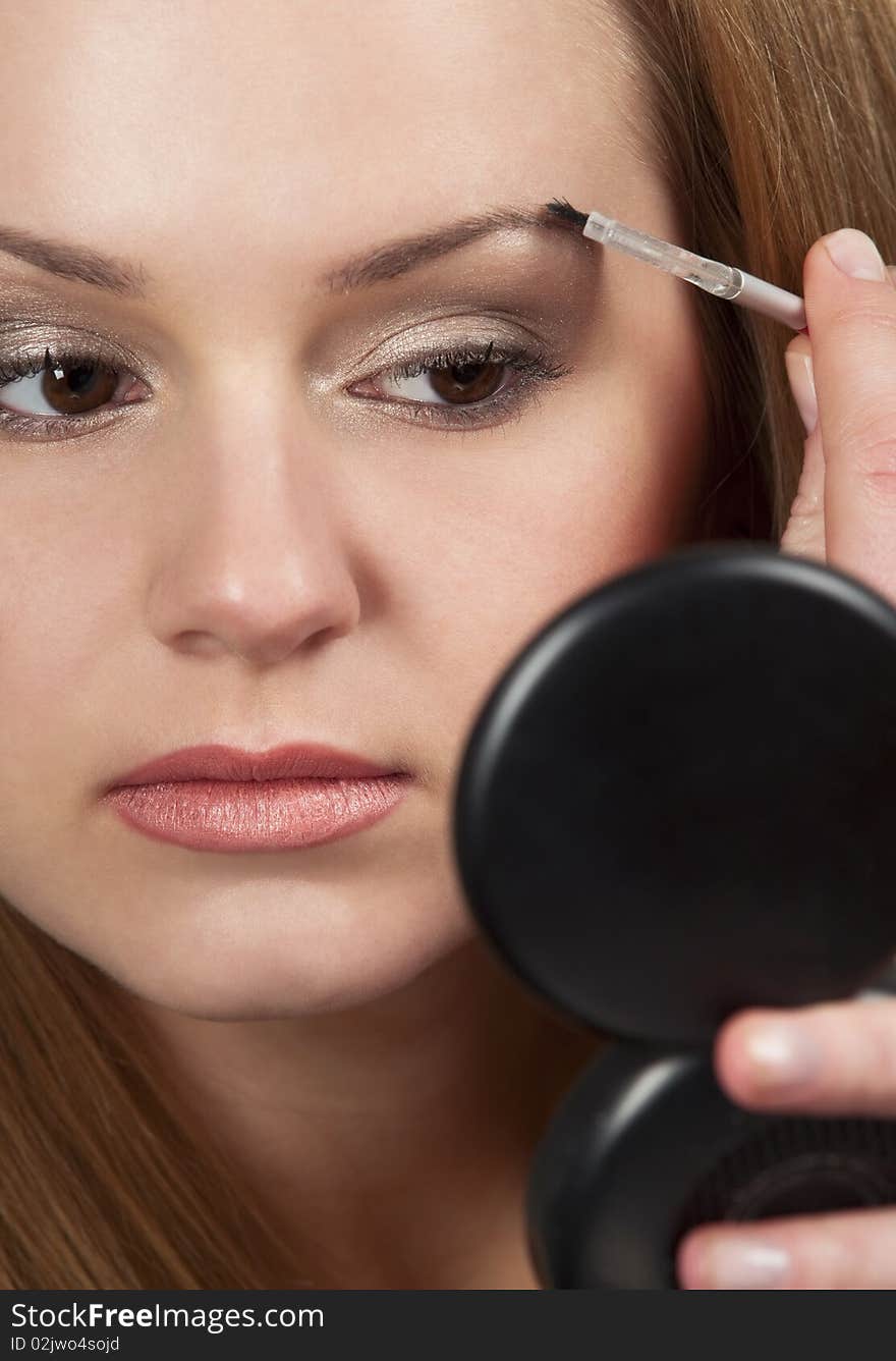 Pretty young woman applying make up.