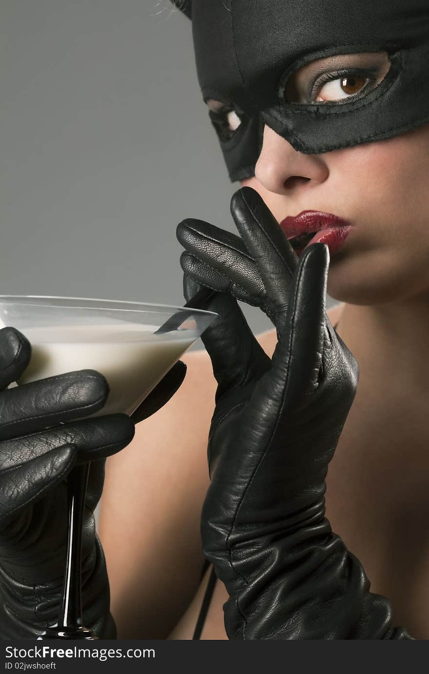 Portrait of the blond girl wearing black cat, licking - drinking milk from the martini glass. Portrait of the blond girl wearing black cat, licking - drinking milk from the martini glass