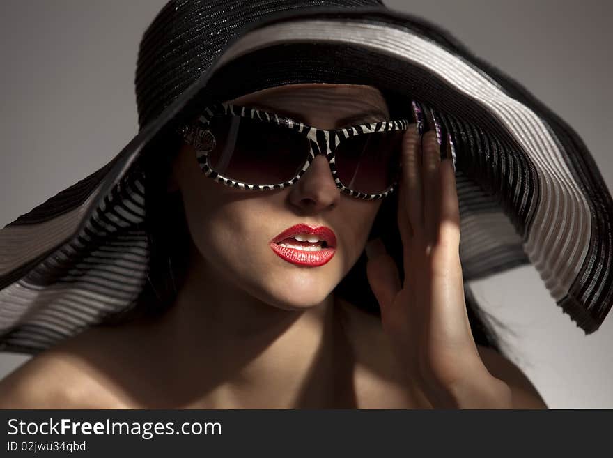 Beautiful model in striped hat and sunglasses on the white background