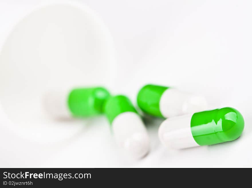 Capsules pouring out of a white glass on white background. Capsules pouring out of a white glass on white background