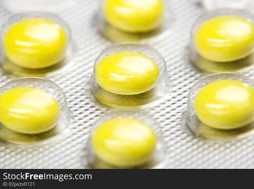 Macro shot of yellow pills` set isolated on white backround