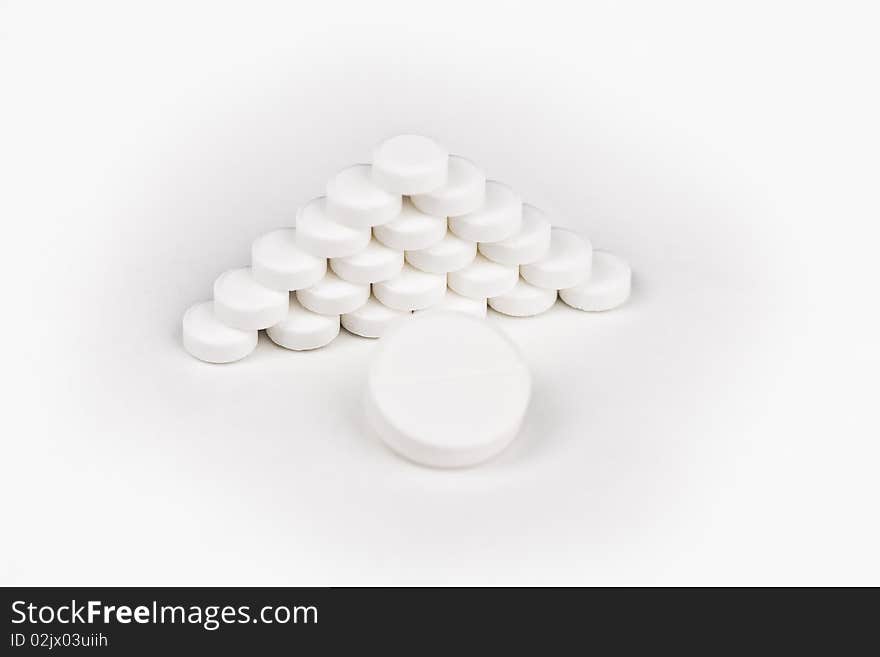 Large white tablet in front of a pyramid of white tablets over wite backround