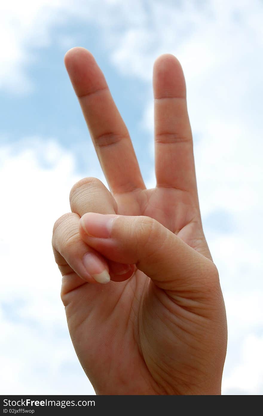 Hand making a peace sign towards with sky as background