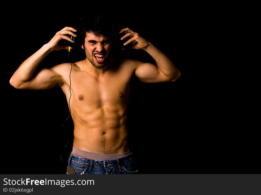 Young Man listening to music with headphones, on black background