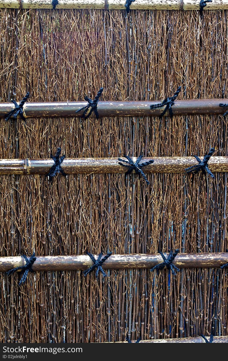 A dark colored bamboo fence in a Shinto temple