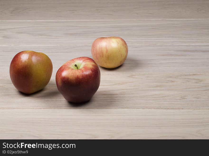 Three apples on  wooden surface