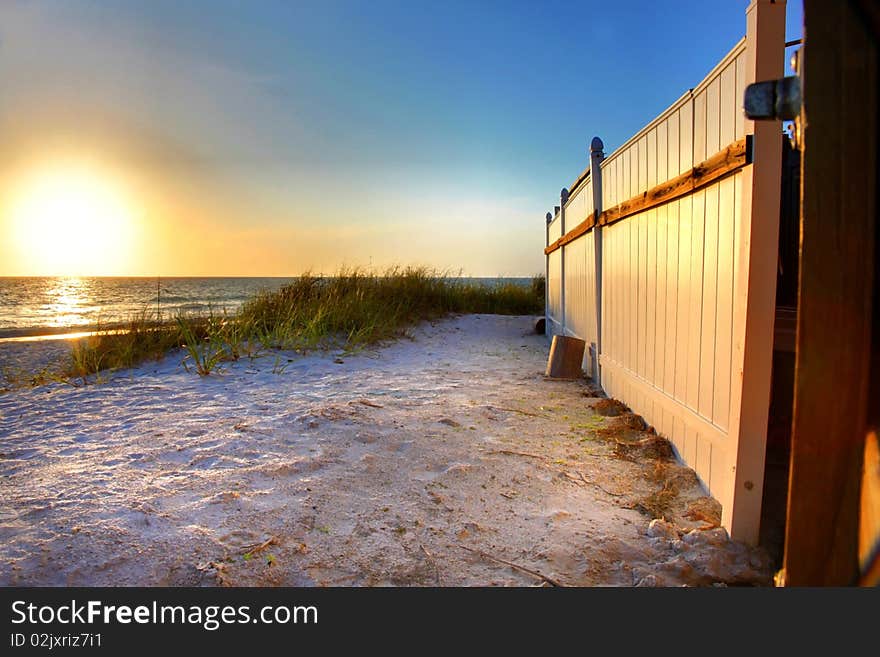 A white fence and white sand on a Florida beach at sunset. A white fence and white sand on a Florida beach at sunset