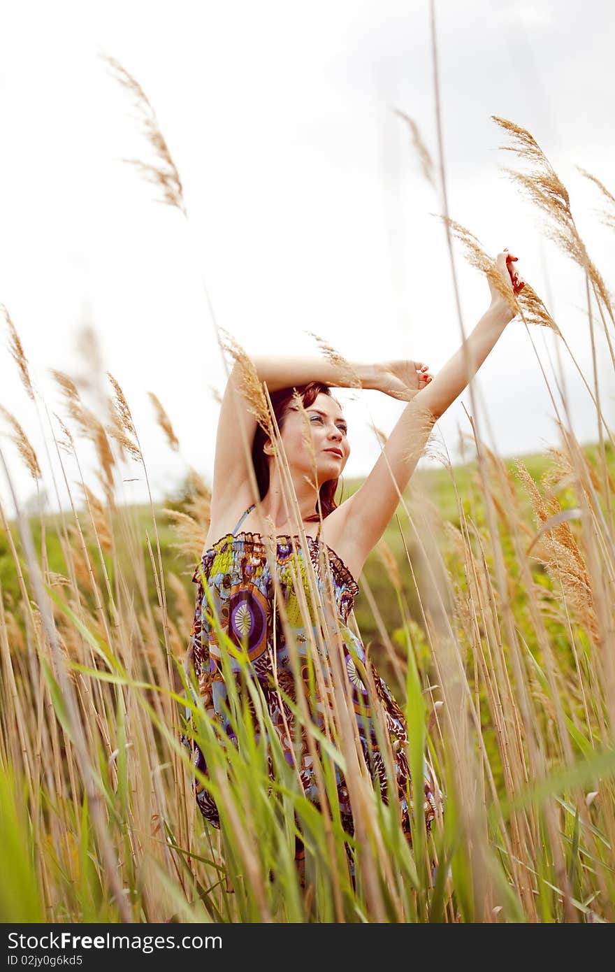 Beautiful young model dancing through the reed in summer. Beautiful young model dancing through the reed in summer