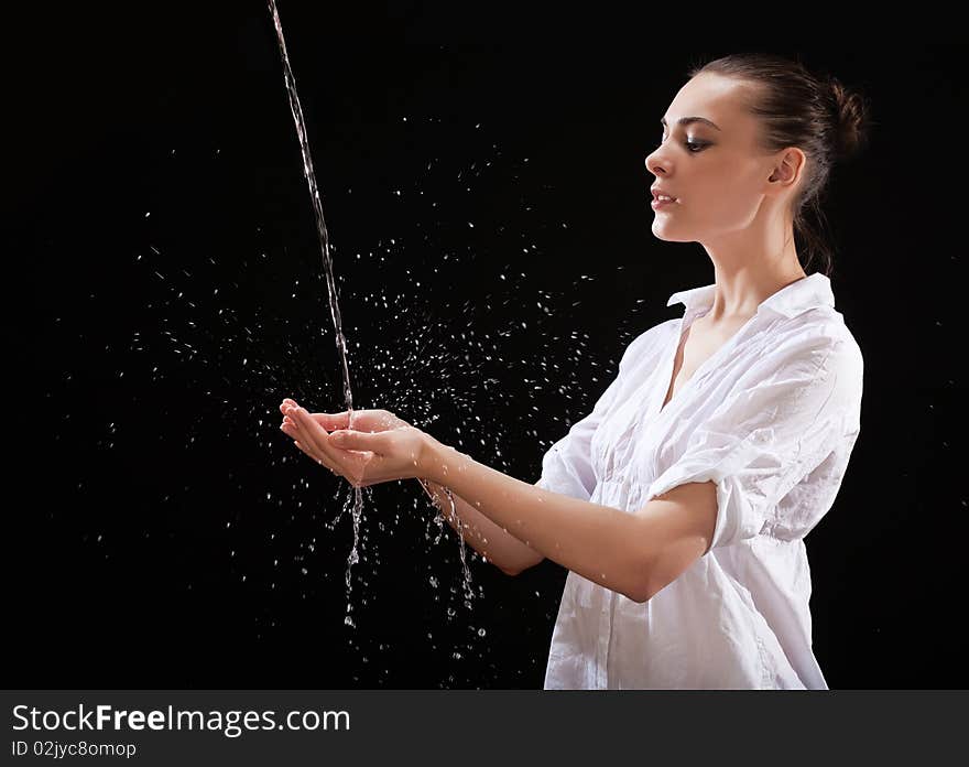 The girl hands catching a water stream on black