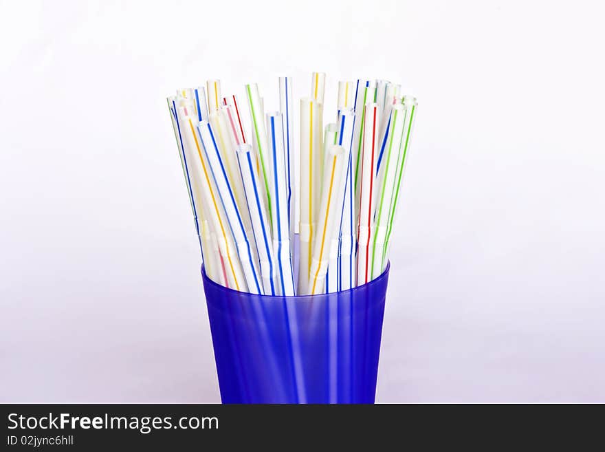 A blue plastic beaker full of colourful drinking straws