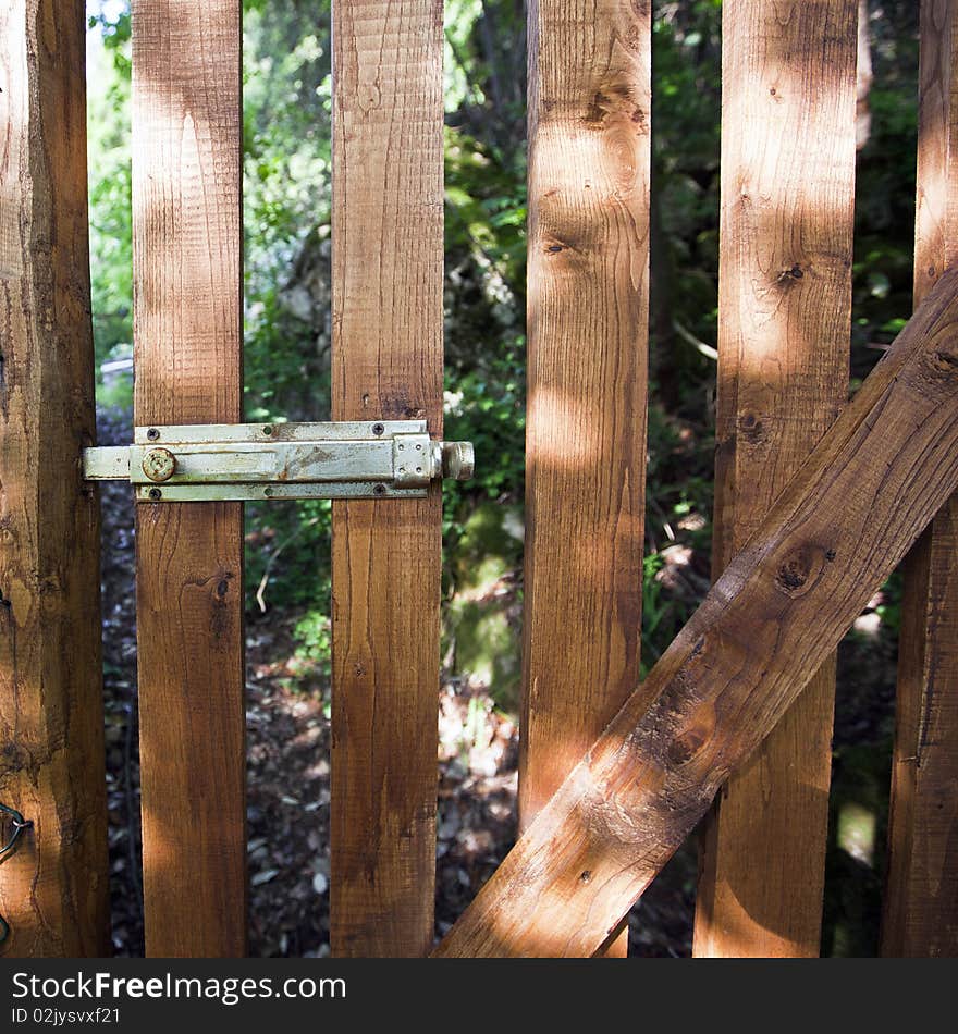 A wooden gate with a metal lever closure. A wooden gate with a metal lever closure