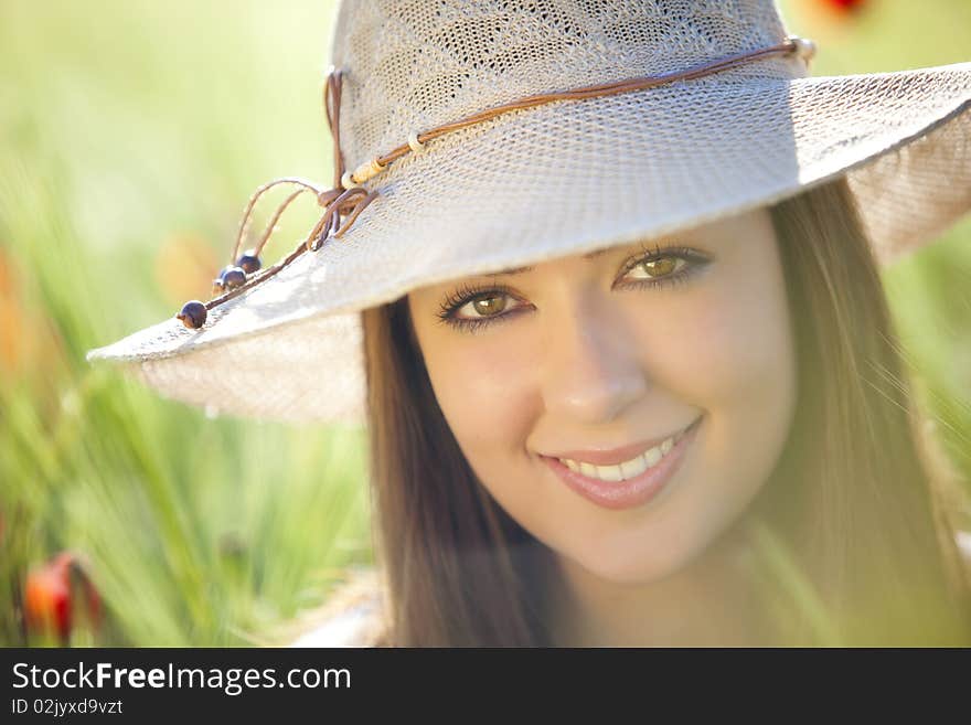 Young beautiful girl with hat staring at camera among green wheat. Young beautiful girl with hat staring at camera among green wheat.