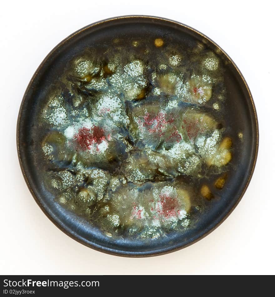 Closeup of traditional Israeli  ceramic circle plate of 50th years with  colorful abstract floral ornament on a black ceramic background. Closeup of traditional Israeli  ceramic circle plate of 50th years with  colorful abstract floral ornament on a black ceramic background.