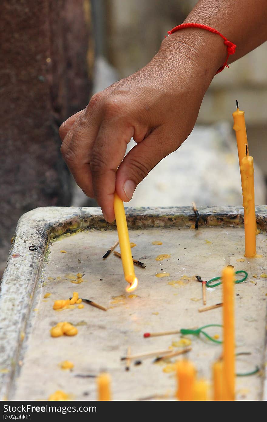 Woman in a temple lighting one candle with another candle. Woman in a temple lighting one candle with another candle