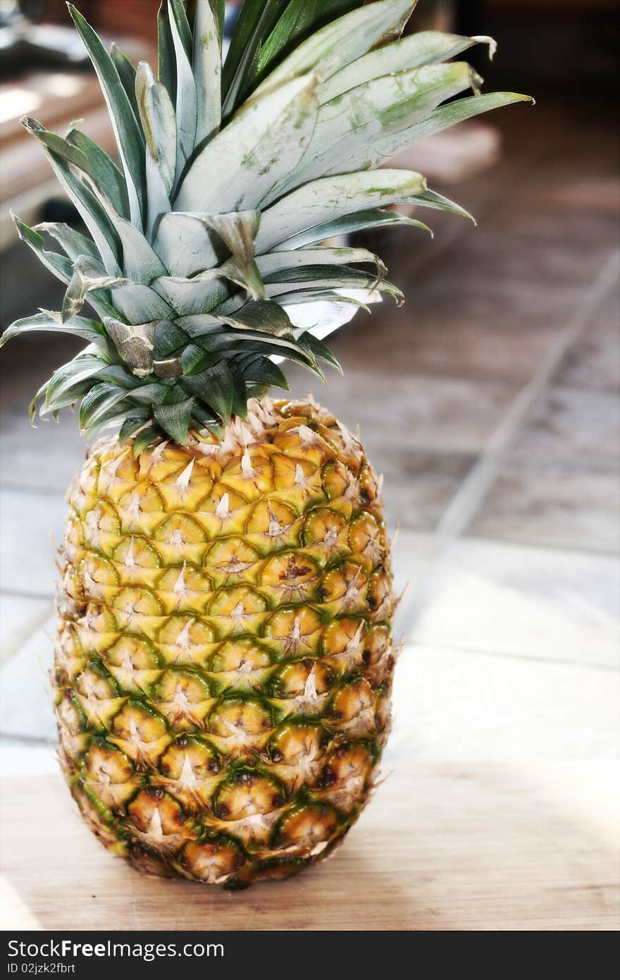 A whole, fresh pineapple sitting on a cutting board.