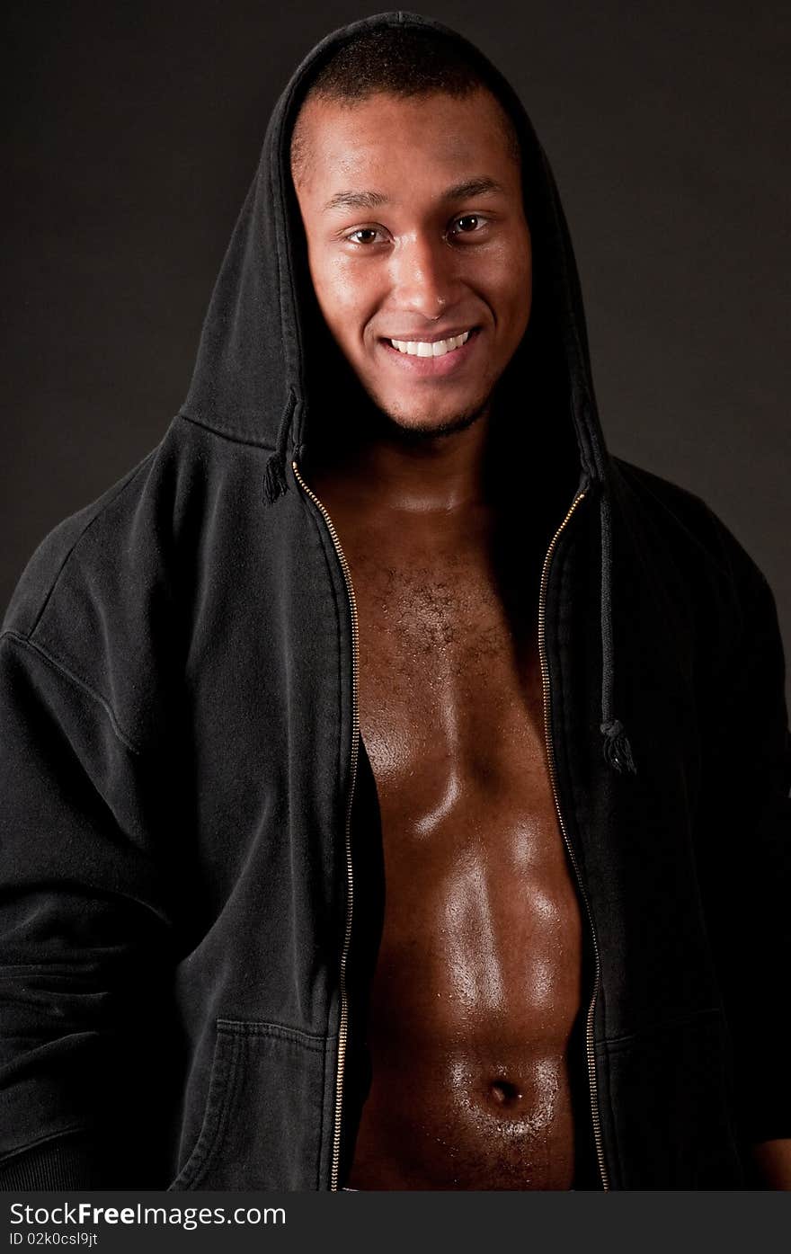 Young muscular male in hood on black background